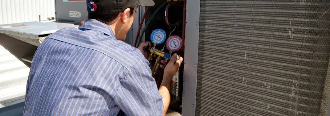 HVAC technician servicing a condenser unit in Lansdowne
